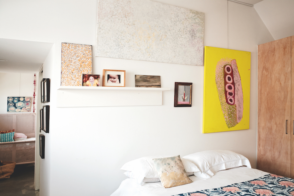 Peggy Brown’s Fire Country Dreaming (left) and Zara Chancellor’s Holkholm (right) are propped alongside family photos. On the wall, (clockwise from top) Kathleen Ngale’s Bush Plum, Rosie Taco King’s Jairnka and Craigie Aitchison’s Bird Candle.