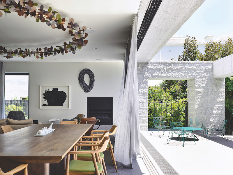 A custom-made ringlight by B.E Architecture hangs above the dining table. A work by Heather B. Swann hangs on the wall next to a wall sculpture by Mark Hilton.